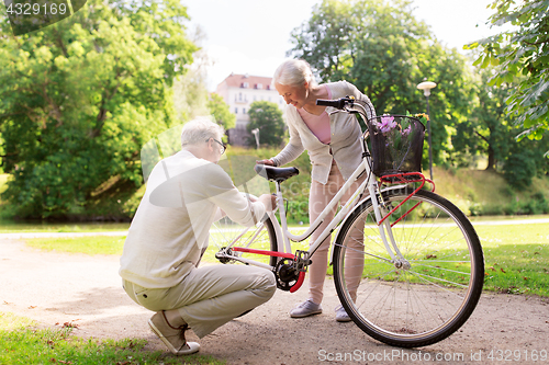 Image of happy senior couple with bicycle at summer park