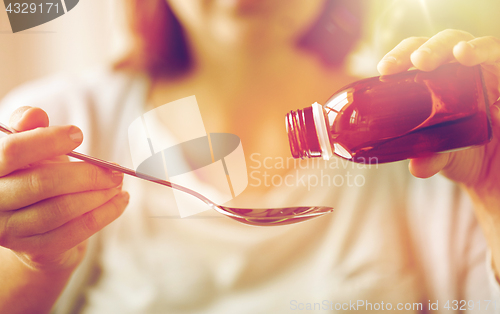 Image of woman pouring medication from bottle to spoon