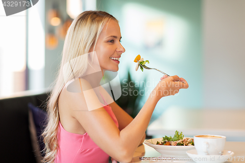 Image of happy young woman eating lunch at restaurant