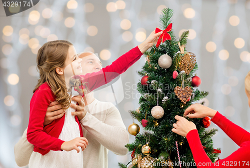 Image of mother, father and daughter at christmas tree