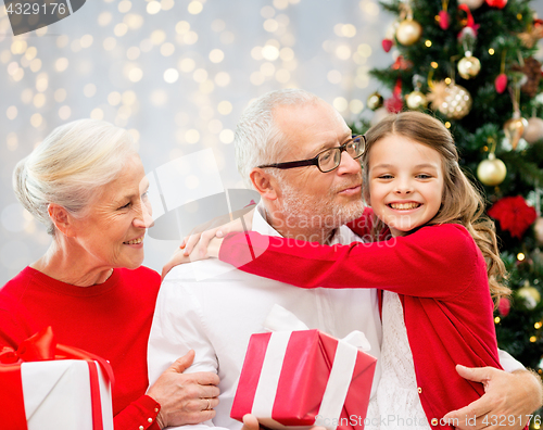 Image of happy family with christmas gifts over lights