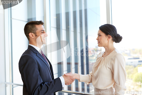 Image of smiling business people shaking hands at office