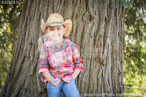 Image of Mixed Race Young Boy Wearing Cowboy Hat Standing Outdoors.