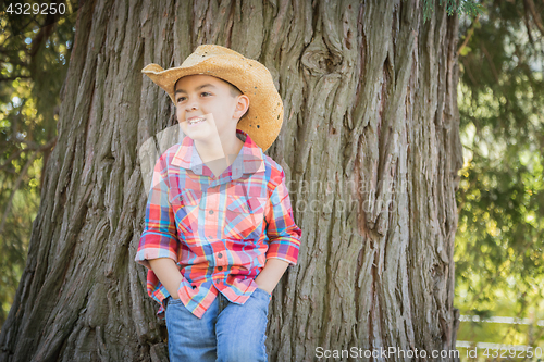 Image of Mixed Race Young Boy Wearing Cowboy Hat Standing Outdoors.