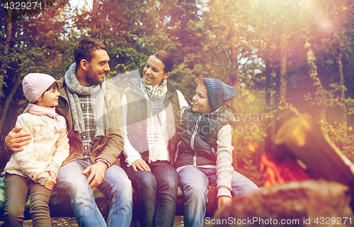 Image of happy family sitting on bench at camp fire