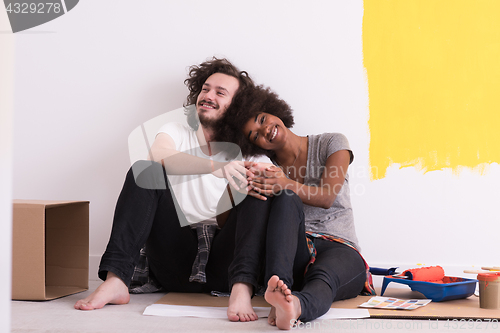 Image of young multiethnic couple relaxing after painting