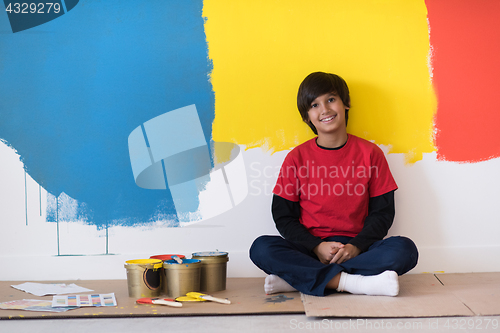 Image of young boy painter resting after painting the wall