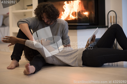 Image of multiethnic couple using tablet computer on the floor