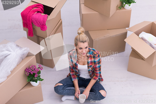 Image of woman with many cardboard boxes sitting on floor