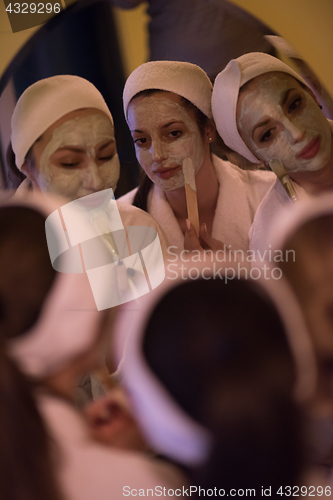 Image of women putting face masks in the bathroom