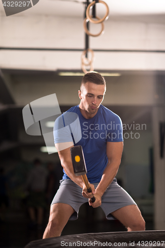 Image of man workout with hammer and tractor tire