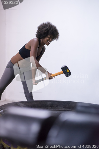 Image of black woman workout with hammer and tractor tire