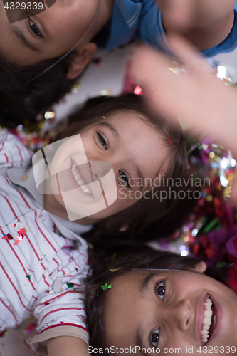 Image of kids  blowing confetti while lying on the floor