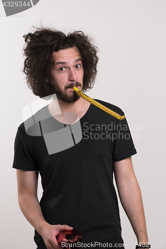 Image of Portrait of a man in party hat blowing in whistle
