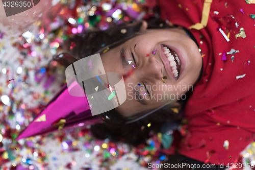 Image of kid blowing confetti while lying on the floor