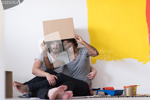 Image of young multiethnic couple playing with cardboard boxes