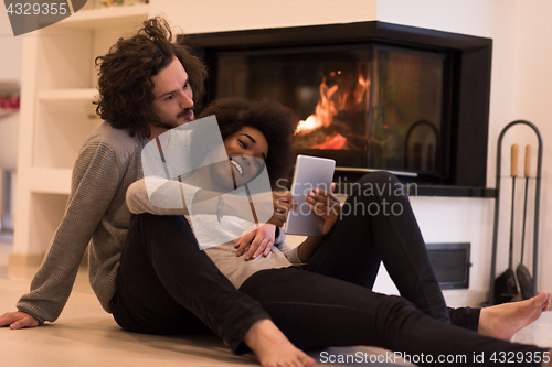 Image of multiethnic couple using tablet computer on the floor