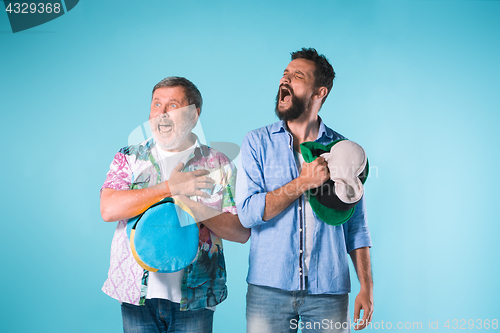 Image of The two football fans singing the national anthem over blue