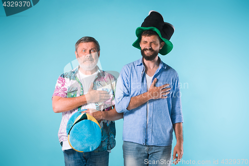 Image of The two football fans singing the national anthem over blue