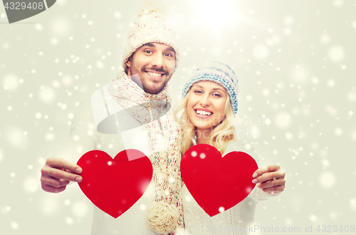 Image of smiling couple in winter clothes with red hearts