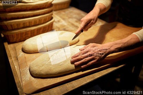 Image of baker making bread and cutting dough at bakery