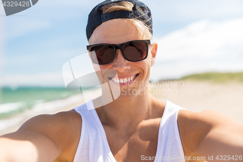 Image of man in sunglasses taking selfie on summer beach