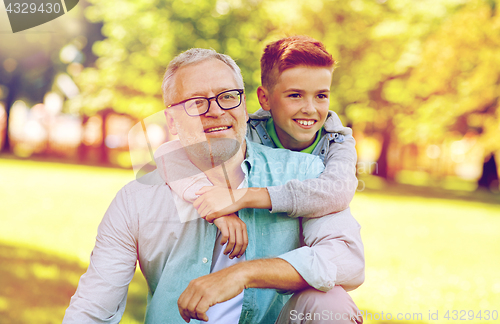 Image of grandfather and grandson hugging at summer park