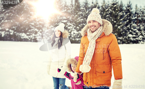 Image of happy family in winter clothes walking outdoors