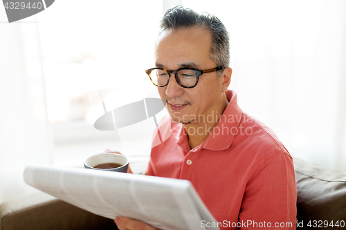 Image of man drinking coffee and reading newspaper at home