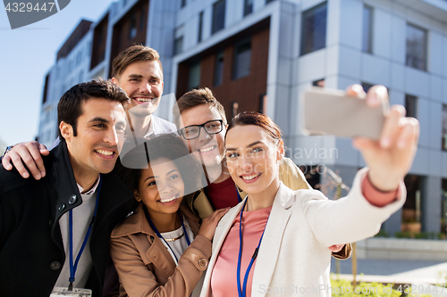 Image of happy people with conference badges taking selfie