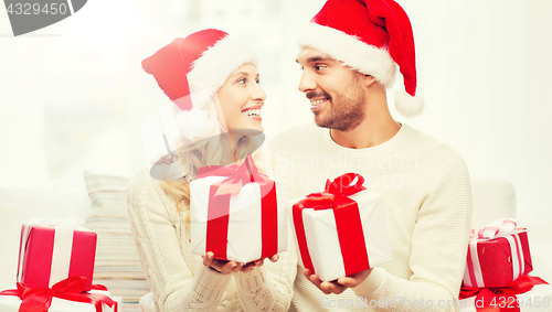 Image of happy couple at home exchanging christmas gifts