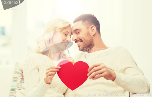 Image of happy couple with red heart hugging at home