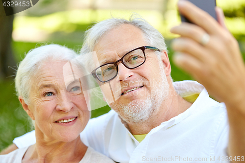 Image of senior couple with smartphone taking selfie in summer