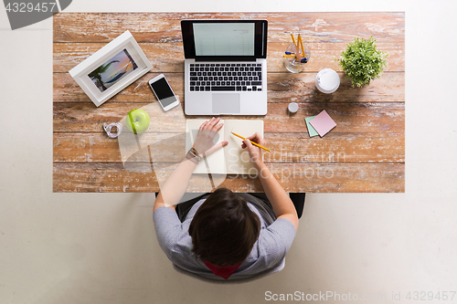 Image of woman drawing to notebook at home office