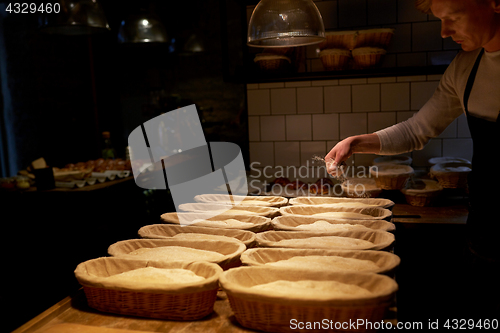 Image of baker with baskets for dough rising at bakery