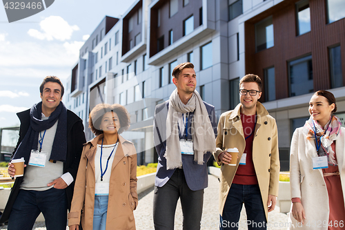 Image of people with coffee and conference badges in city