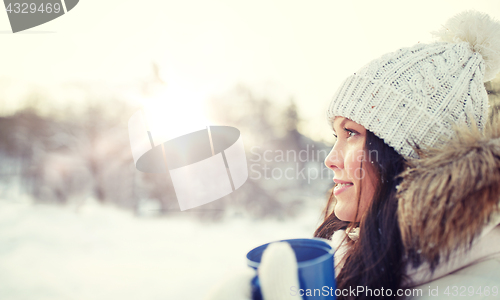 Image of happy young woman with tea cup outdoors in winter
