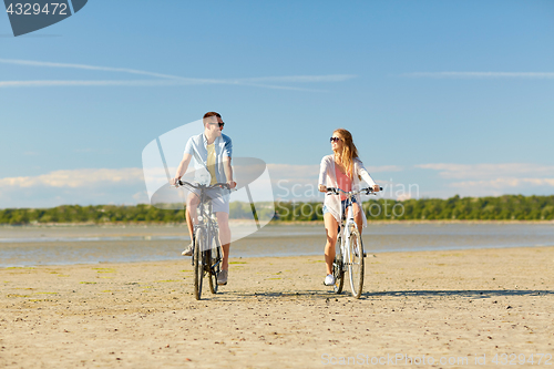 Image of happy young couple riding bicycles at seaside