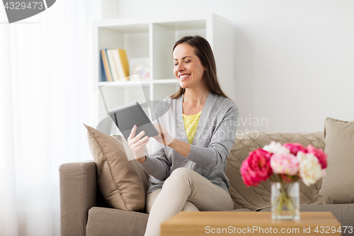 Image of happy woman with tablet pc at home