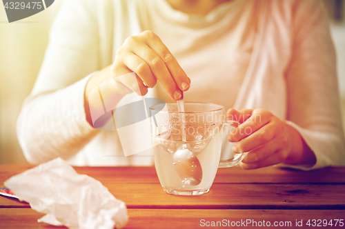 Image of woman stirring medication in cup with spoon