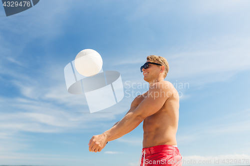 Image of young man with ball playing volleyball on beach