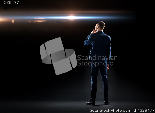 Image of businessman over black looking at laser light