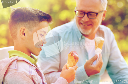 Image of old man and boy eating ice cream at summer park