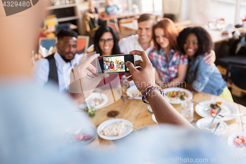 Image of friends taking picture by smartphone at restaurant