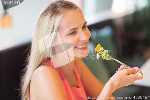 Image of happy young woman eating at restaurant