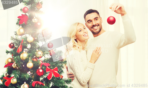 Image of happy couple decorating christmas tree at home