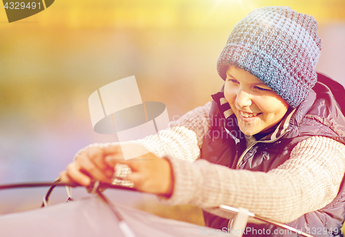 Image of happy boy setting up tent outdoors