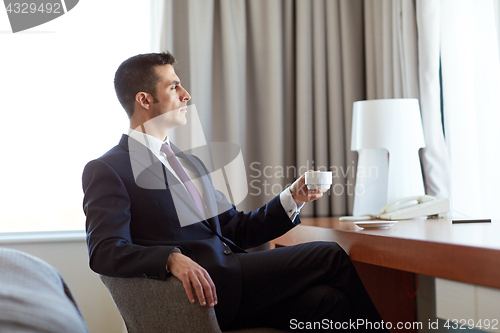 Image of businessman drinking coffee at hotel room