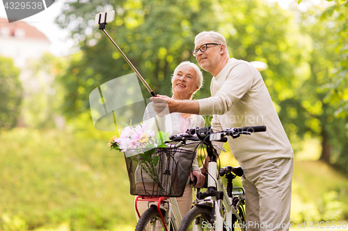 Image of senior couple with bicycles taking selfie at park