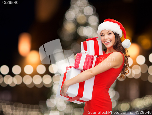 Image of smiling woman in santa hat with gift boxes